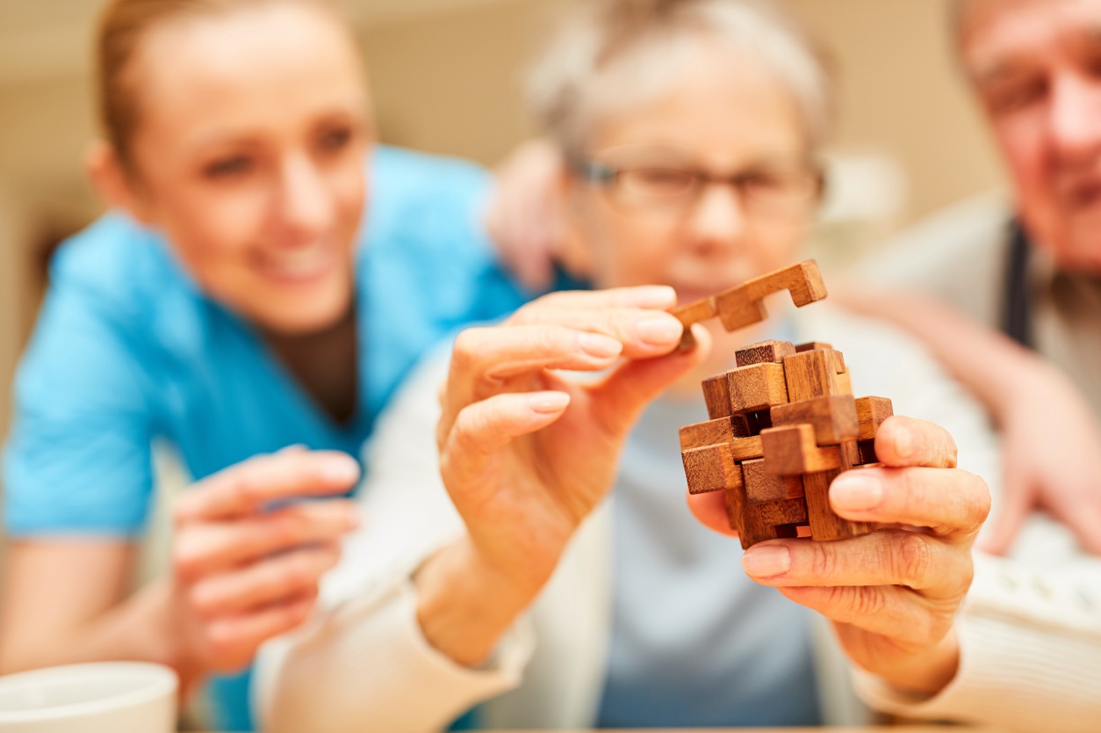 An Otter Care Professional doing a wooden puzzle with an older couple at home