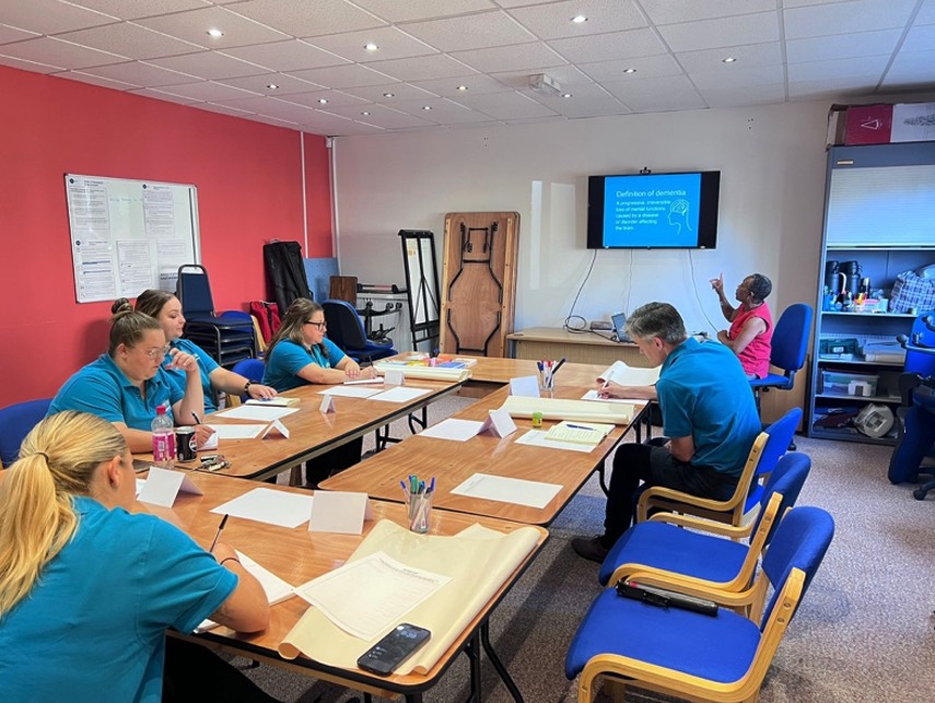 The Otter team in a dementia training session, with a trainer presenting a 'Definition of dementia' slide