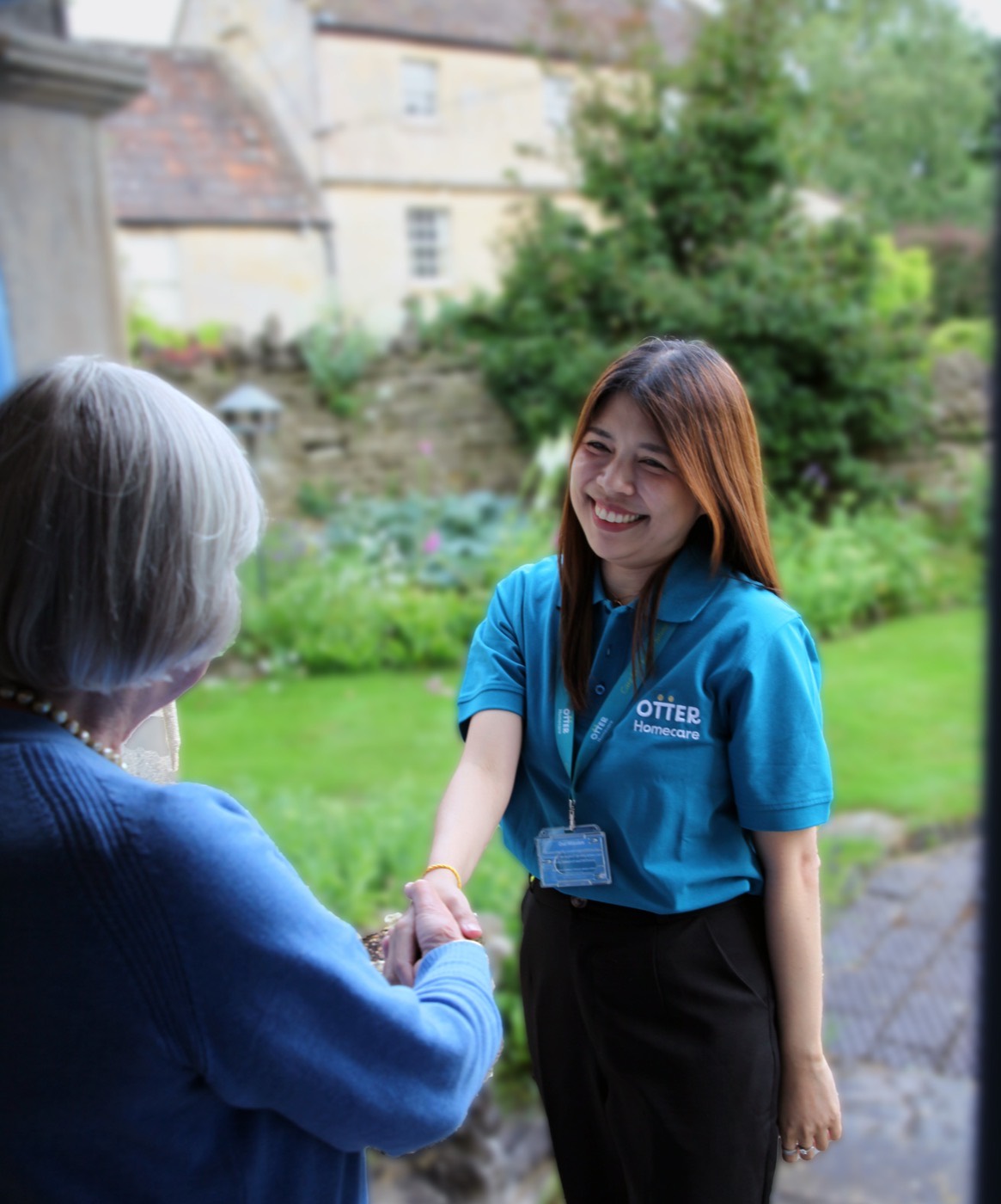 An Otter Care Professional warmly greeting a client at her front door